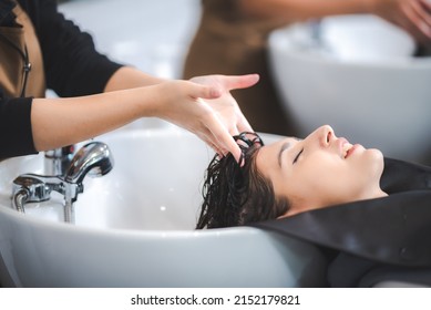 young beautiful woman client getting hair treatment in beauty salon with professional female stylist hairdresser, using shampoo and water on person head to clean and coiffure hair fashion service