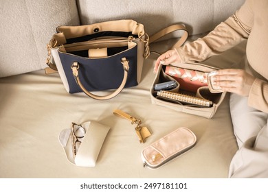 A young beautiful woman is collecting her women's bag. Places your diary, glasses, keys, and phone in an organizer. Concept of organization and storage in a daily women's bag.