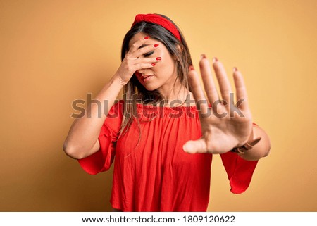 Young beautiful woman colorful summer style over yellow isolated background covering eyes with hands and doing stop gesture with sad and fear expression. Embarrassed and negative concept.