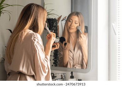 A young beautiful woman combs her long hair and takes care of her skin in the morning at home in front of the mirror. Beauty and hygiene concept. - Powered by Shutterstock