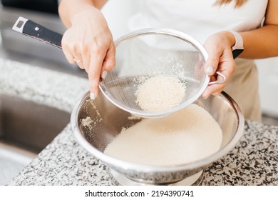 A Young Beautiful Woman Cooks In A Bright Kitchen. Cooking Macaroons. A Cute Girlp Repares Dough For Cakes, Hands And Ingrident Closeup. Cooking Macaroons. Cookie Baking