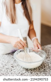 A Young Beautiful Woman Cooks In A Bright Kitchen. Cooking Macaroons. A Cute Girlp Repares Dough For Cakes, Hands And Ingrident Closeup. Cooking Macaroons. Cookie Baking