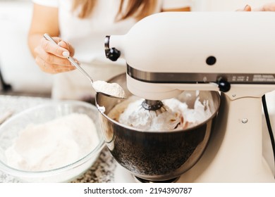 A Young Beautiful Woman Cooks In A Bright Kitchen. Cooking Macaroons. A Cute Girlp Repares Dough For Cakes, Hands And Ingrident Closeup. Cooking Macaroons. Cookie Baking