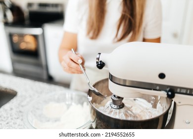 A Young Beautiful Woman Cooks In A Bright Kitchen. Cooking Macaroons. A Cute Girlp Repares Dough For Cakes, Hands And Ingrident Closeup. Cooking Macaroons. Cookie Baking