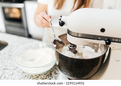 A Young Beautiful Woman Cooks In A Bright Kitchen. Cooking Macaroons. A Cute Girlp Repares Dough For Cakes, Hands And Ingrident Closeup. Cooking Macaroons. Cookie Baking