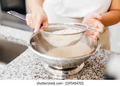 A Young Beautiful Woman Cooks In A Bright Kitchen. Cooking Macaroons. A Cute Girlp Repares Dough For Cakes, Hands And Ingrident Closeup. Cooking Macaroons. Cookie Baking