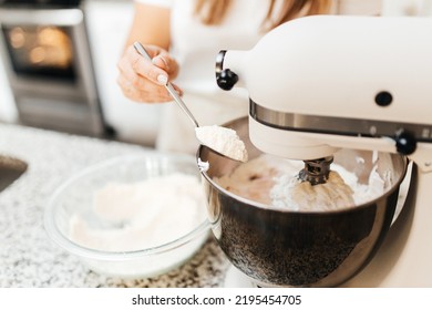 A Young Beautiful Woman Cooks In A Bright Kitchen. Cooking Macaroons. A Cute Girlp Repares Dough For Cakes, Hands And Ingrident Closeup. Cooking Macaroons. Cookie Baking