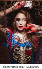 Young Beautiful Woman In A Costume Queen Of Hearts And Make-up Holds Playing Cards In Their Hands. Background Of Creative Decor And Old Rusty Metal. Halloween. Preparation For A Costume Party.