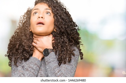Young beautiful woman with curly hair wearing grey sweater shouting and suffocate because painful strangle. Health problem. Asphyxiate and suicide concept.
