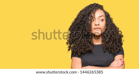 Young beautiful woman with curly hair smiling looking side and staring away thinking.