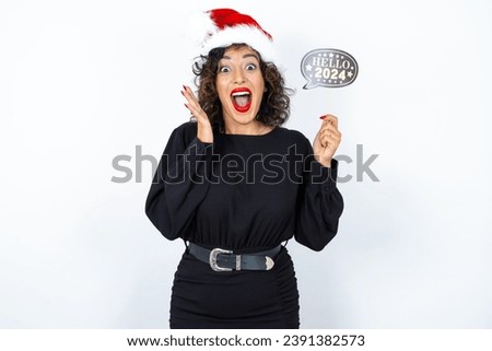 Young beautiful woman with curly hair wearing black dress over white studio background holding a Happy New year 2024 banner. 