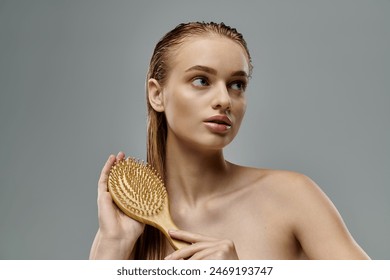 A young beautiful woman demonstrating her hair care routine with wet hair, holding a hairbrush. - Powered by Shutterstock