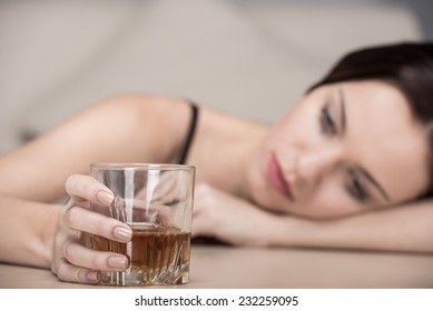 Young beautiful woman in depression, is drinking alcohol.