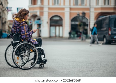 Young beautiful woman with disability who uses a wheelchair using a smartphone while out in the city - Powered by Shutterstock