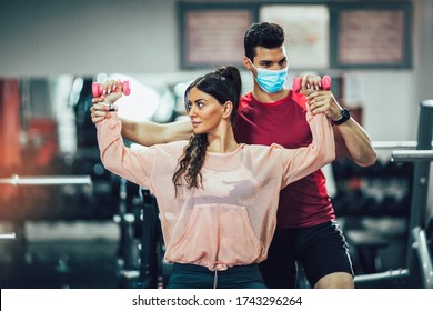 Young Beautiful Woman Doing Exercises With Personal Trainer. Man Wearing Face Mask