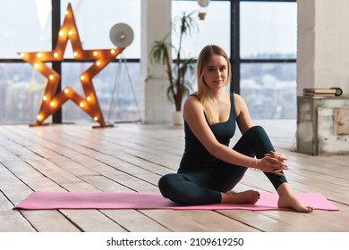 Young Beautiful Woman Doing Yoga In A Modern Bright Room With Large Windows. Yoga At Home Concept