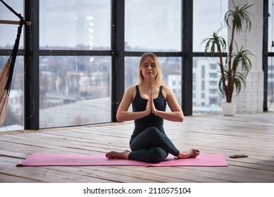 Young Beautiful Woman Doing Yoga In A Modern Bright Room With Large Windows. Yoga At Home Concept