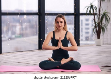 Young Beautiful Woman Doing Yoga In A Modern Bright Room With Large Windows. Yoga At Home Concept