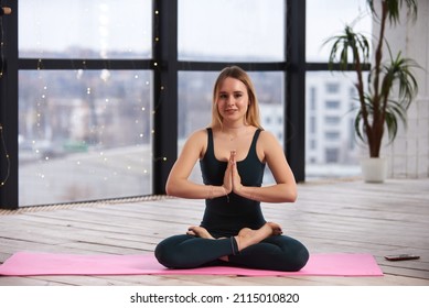 Young Beautiful Woman Doing Yoga In A Modern Bright Room With Large Windows. Yoga At Home Concept