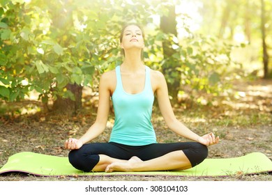 Young Beautiful Woman Doing Yoga Exercises In Park