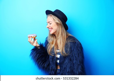 Young beautiful woman with doughnut on blue background