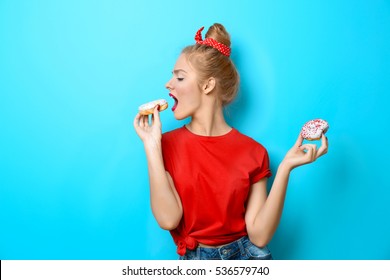 Young beautiful woman with doughnuts on blue background