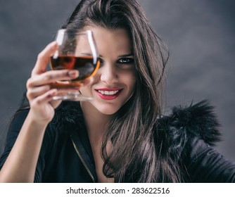 Young Beautiful Woman Drinking Alcohol On Dark Background. Focus On Woman