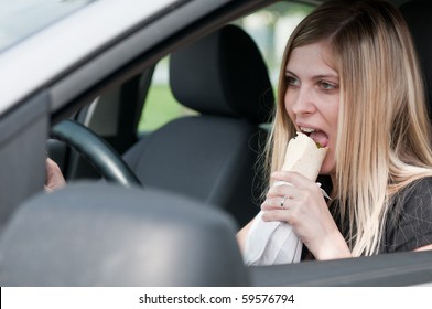 Young Beautiful Woman Driving Car And Eating Fast Food With Mouth Wide Open