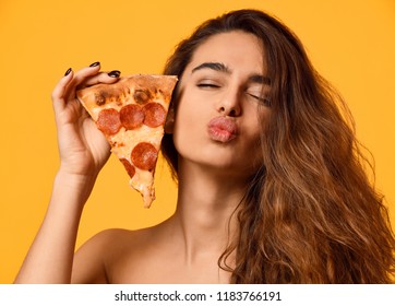 Young beautiful woman eat hold pepperoni pizza slice show kissing sign with lips on yellow background