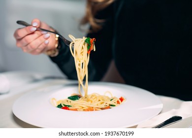 Young beautiful woman eating pasta in a restaurant