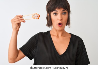 Junge schöne Frau, die Sushi mit Stäbchen isst, die auf einzeln weißem Hintergrund stehen und Angst vor Schock mit Überraschung, Angst und Aufregung vor Angstausdrücken haben