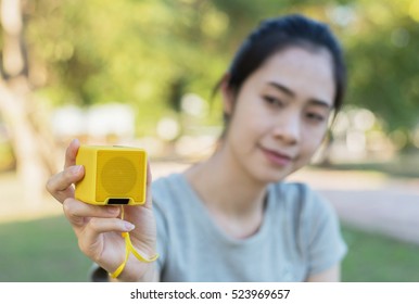 Young Beautiful Woman Enjoying The Music At  Outdoor Park.Woman Listening Music By Bluetooth Speaker At  Outdoor Park.