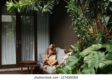Young beautiful woman enjoys relaxing on the terrace of a resort hotel in Bali. - Shutterstock ID 2174300305