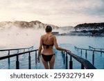 Young beautiful woman enjoys thermal bath at sunrise inside the Blue Lagoon Spa, Iceland.