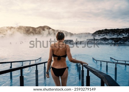 Young beautiful woman enjoys thermal bath at sunrise inside the Blue Lagoon Spa, Iceland.