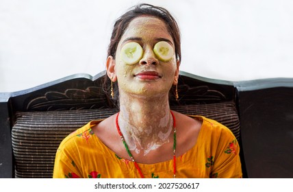 Young Beautiful Woman With Face Pack And Fresh Cucumber Slices On Her Eyes. Homemade Facial Mask At Home. Multani Soil Face-pack Looking Like A Gold Facial. Beauty, Healthcare