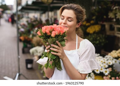 Young and beautiful woman florist with a heap of rose flowers in her little flower shop - Powered by Shutterstock