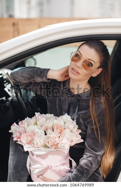 Young beautiful woman with flowers in the car.
Spring. Summer.