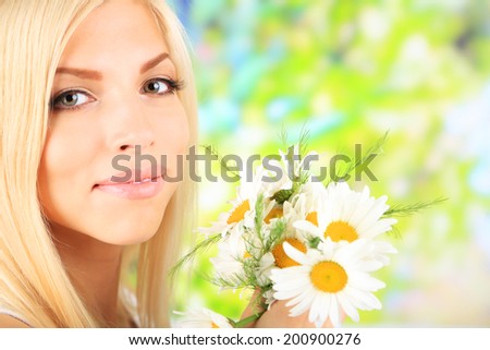 Young beautiful woman with flowers on bright background