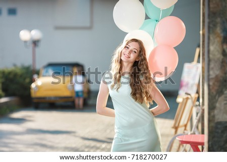 young beautiful woman with flying multicolored balloons in the city 