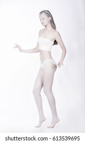 Young Beautiful Woman In Full Growth In White Paint Posing In Studio. Body Art.