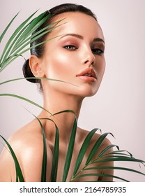 Young Beautiful Woman With Green Leaves Near Face And Body. Skin Care Beauty Treatments Concept.  Closeup Girl's Face With Green Leave. White Model With Clean, Health Skin Of Face - Posing At Studio