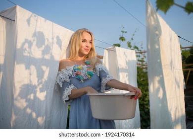 Young beautiful woman hanging up laundry outdoors.  Spring Awakening. cottagecore. slow life. pastoral life.  enjoy the little things.  Dreaming of Spring
