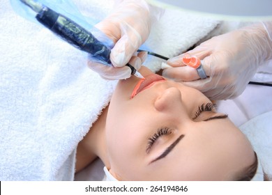 Young beautiful woman having permanent make-up (Tattoo)