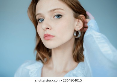 Young beautiful woman with healthy flawless radiant freckled skin posing on light blue background. Close up studio beauty portrait. Natural day light.  Copy, empty space for text - Shutterstock ID 2364804015