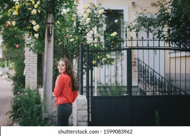 Young Beautiful Woman With Healthy Long Hair Wearing Red Shirt Posing In A Park. Street Style And Fashion.