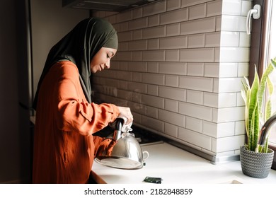 Young Beautiful Woman In Hijab Making Tea In Cozy Kitchen At Home