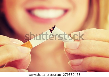 Young beautiful woman holding broken cigarette in front.