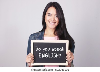 Young beautiful woman holding a chalkboard that says Do You Speak English? 