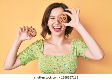 Young beautiful woman holding cookies smiling and laughing hard out loud because funny crazy joke. 